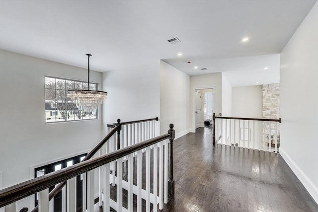 corridor with baseboards, visible vents, dark wood-type flooring, and an upstairs landing