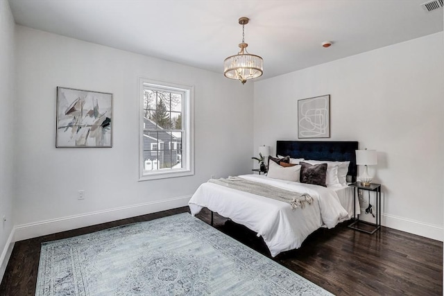 bedroom featuring dark wood-style floors, baseboards, visible vents, and a notable chandelier