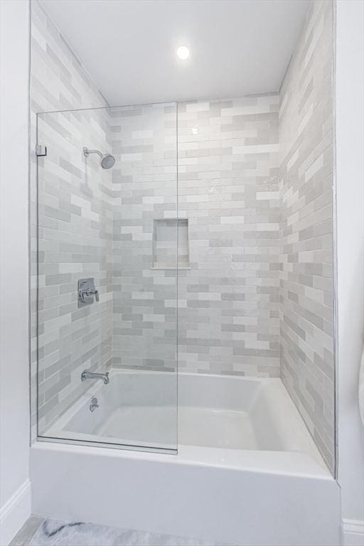 bathroom featuring bath / shower combo with glass door and baseboards