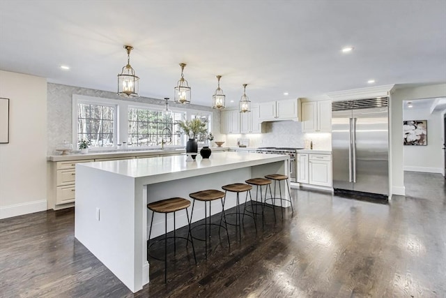 kitchen with white cabinetry, a center island, light countertops, and high quality appliances