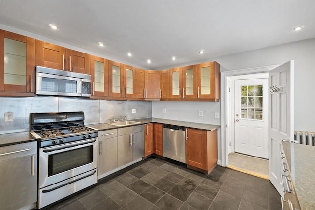 kitchen featuring glass insert cabinets, brown cabinets, and appliances with stainless steel finishes