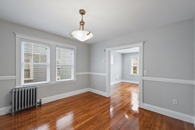 unfurnished room featuring radiator heating unit, baseboards, and hardwood / wood-style flooring