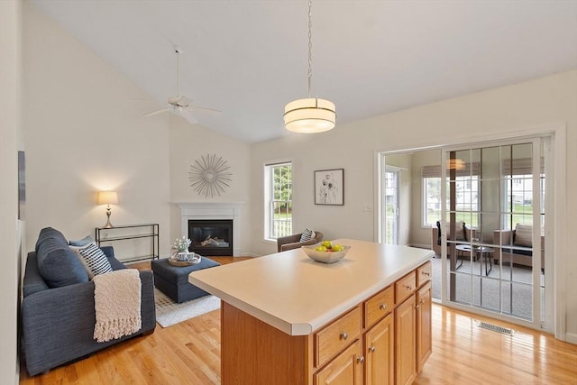 45 Augusta Way Unit 23, Chelmsford, MA 01863 - kitchen with open floor plan, light wood-style floors, light countertops, a center island, and a glass covered fireplace