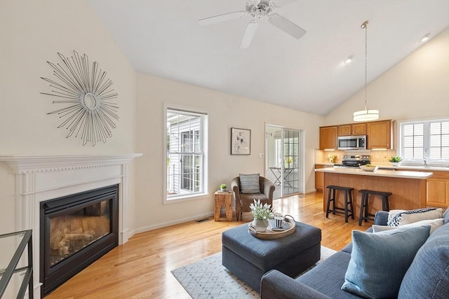 45 Augusta Way Unit 23, Chelmsford, MA 01863 - living room featuring light wood-type flooring, healthy amount of natural light, a glass covered fireplace, a ceiling fan, and high vaulted ceiling