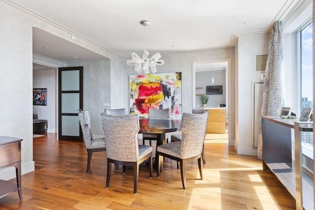 dining room with a chandelier, crown molding, light wood-style flooring, and baseboards