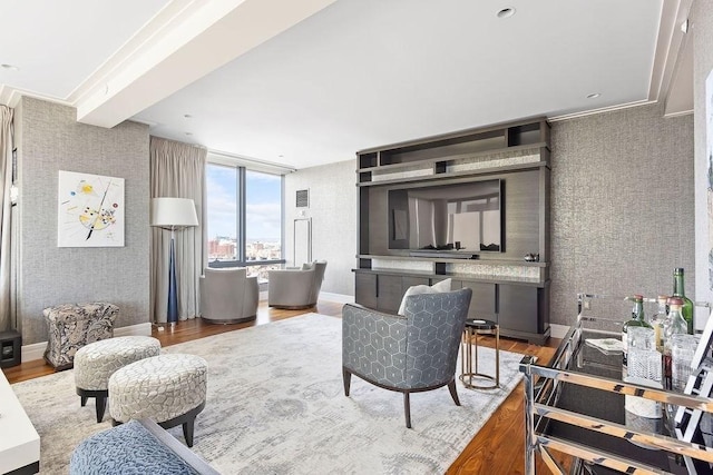 living area with wallpapered walls, wood finished floors, and baseboards