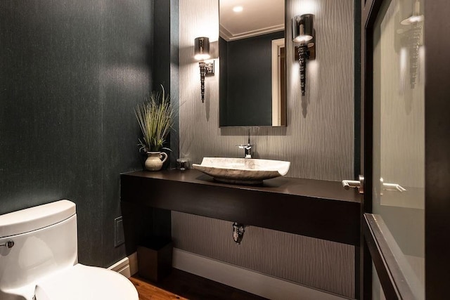 half bath with toilet, crown molding, wood finished floors, and vanity