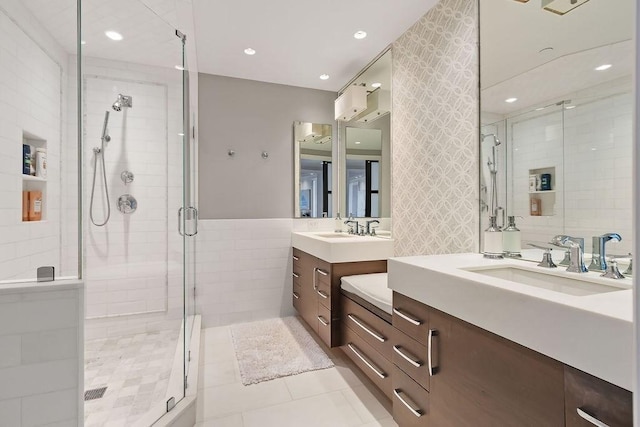bathroom featuring a shower stall, tile patterned flooring, two vanities, recessed lighting, and tile walls