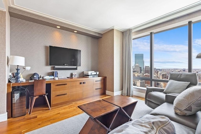 living area with light wood-type flooring, baseboards, a desk, and expansive windows