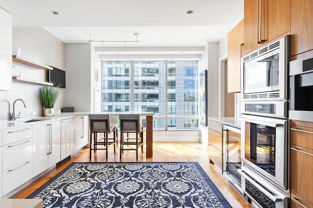 kitchen featuring modern cabinets, a sink, healthy amount of natural light, stainless steel appliances, and crown molding