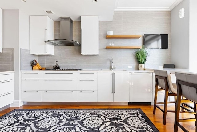 kitchen with wall chimney exhaust hood, a sink, modern cabinets, gas cooktop, and backsplash