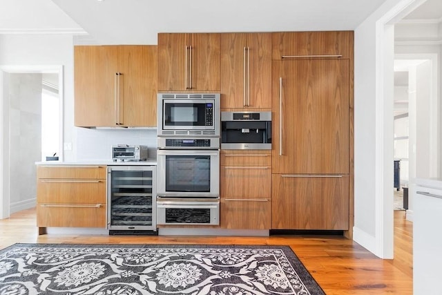 kitchen with beverage cooler, built in appliances, and modern cabinets