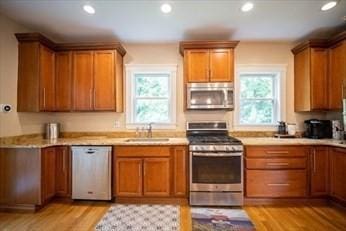 kitchen with a sink, appliances with stainless steel finishes, brown cabinetry, and light countertops