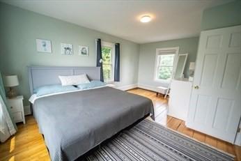 bedroom with multiple windows, light wood-style flooring, and baseboards