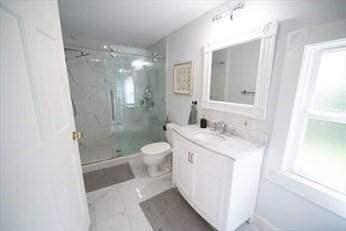 bathroom with toilet, vanity, and a marble finish shower