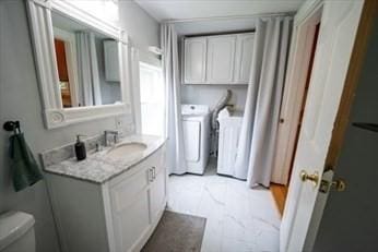 bathroom featuring toilet, vanity, and washing machine and clothes dryer