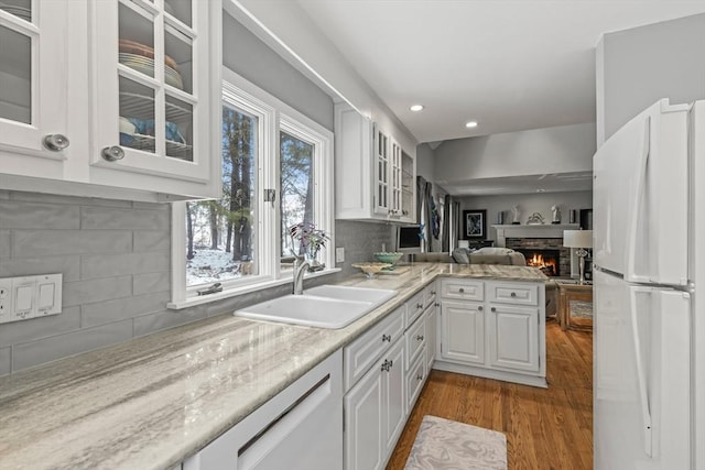 kitchen featuring glass insert cabinets, open floor plan, freestanding refrigerator, white cabinetry, and a sink