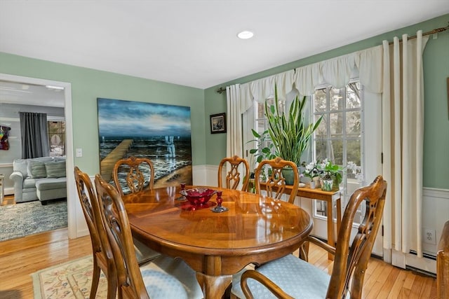 dining space with light wood-style floors and a wainscoted wall