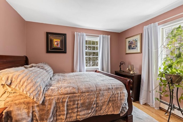 bedroom with a baseboard radiator and light wood-style flooring