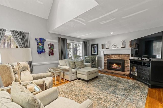 living room with lofted ceiling, a fireplace, and wood finished floors