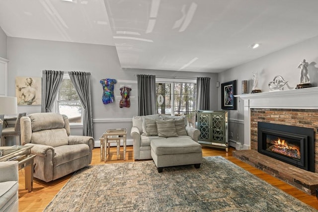 living room featuring baseboards, a baseboard radiator, wood finished floors, a fireplace, and a baseboard heating unit