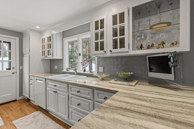 bar with tasteful backsplash, recessed lighting, light wood-style flooring, stainless steel dishwasher, and a sink