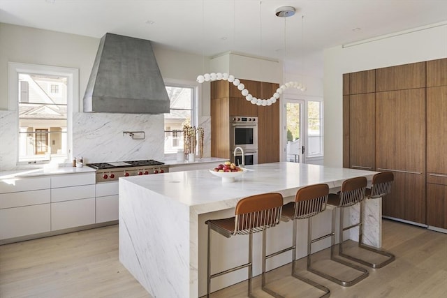 kitchen featuring a spacious island, appliances with stainless steel finishes, custom exhaust hood, backsplash, and white cabinetry