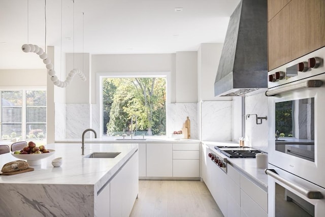 kitchen featuring white cabinets, double oven, stainless steel gas cooktop, and sink