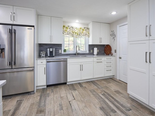 kitchen featuring a sink, light countertops, light wood-type flooring, and stainless steel appliances