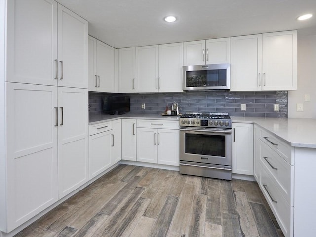 kitchen with stainless steel appliances, white cabinetry, wood finished floors, and light countertops