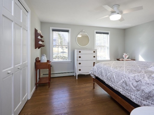 bedroom featuring dark wood-type flooring, multiple windows, a closet, and a baseboard radiator