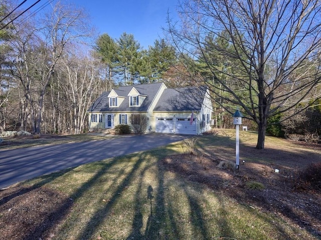 cape cod home featuring a garage, a front lawn, and driveway