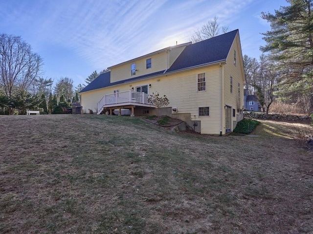 rear view of property featuring a wooden deck and a lawn