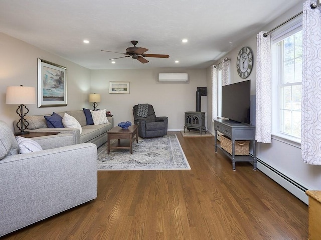 living area with dark wood-style floors, a healthy amount of sunlight, an AC wall unit, and a baseboard radiator