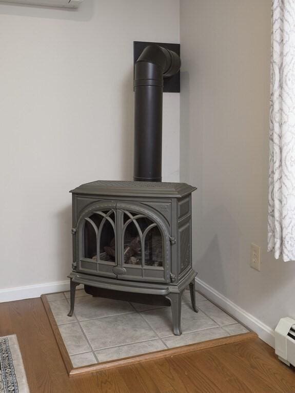 room details featuring a wood stove, wood finished floors, and baseboards