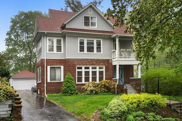 view of front facade with an outdoor structure, a balcony, a detached garage, and brick siding
