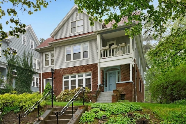 view of front of home with a balcony and brick siding