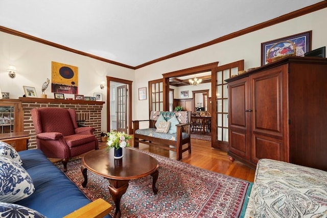 living room featuring a chandelier, wood finished floors, a fireplace, and ornamental molding