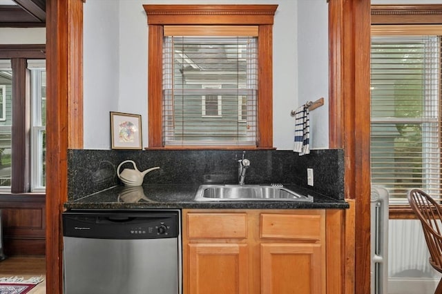 kitchen featuring dishwasher, a sink, dark countertops, and tasteful backsplash