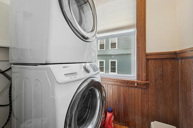 laundry room featuring stacked washer / dryer and wood walls
