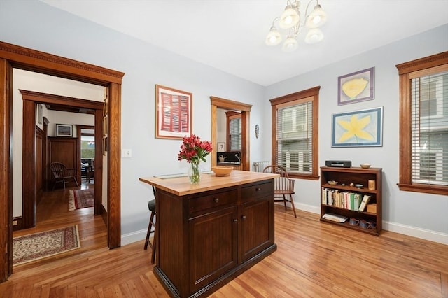 kitchen with a chandelier, butcher block countertops, light wood-style flooring, baseboards, and a desk