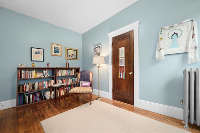 sitting room with radiator heating unit, baseboards, and hardwood / wood-style floors
