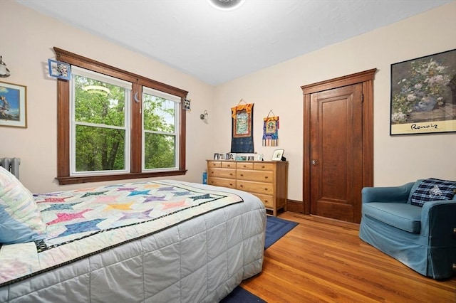 bedroom with light wood-style flooring, baseboards, and radiator