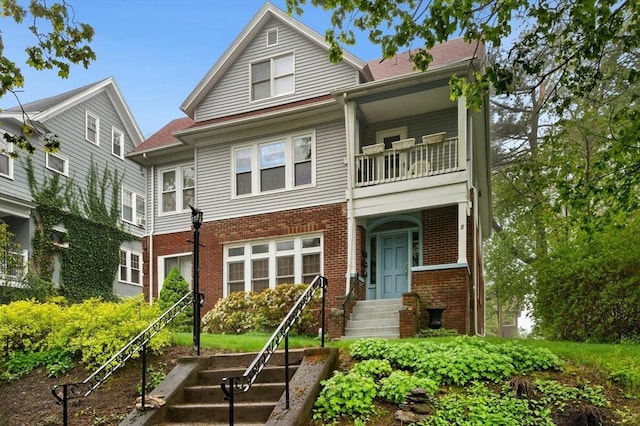 multi unit property featuring a balcony and brick siding