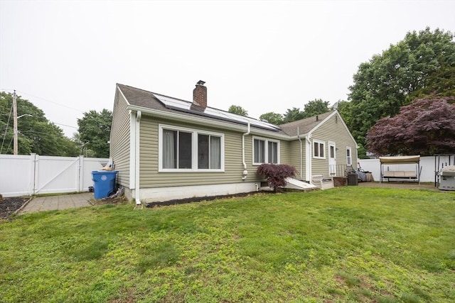 109 Circle Dr, Wrentham, MA 02093 - rear view of house featuring a gate, roof mounted solar panels, and a chimney