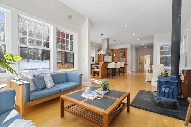 living room featuring plenty of natural light, a wood stove, and light wood finished floors