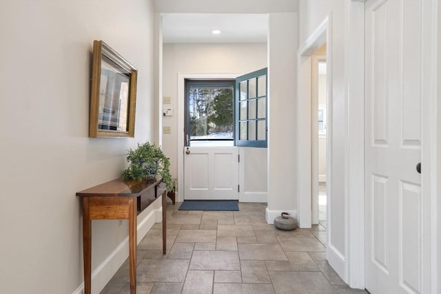 doorway to outside featuring baseboards, stone finish floor, and recessed lighting