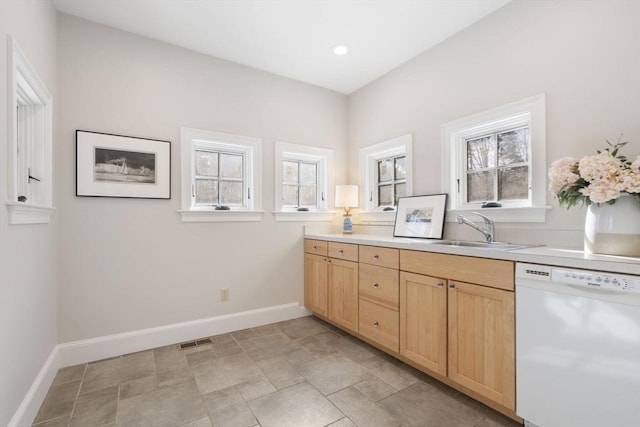 kitchen with visible vents, light brown cabinetry, baseboards, a sink, and dishwasher