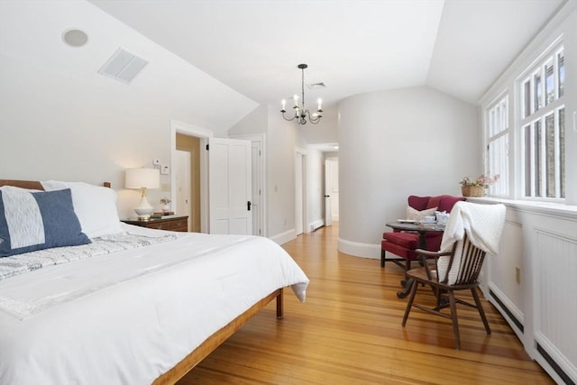 bedroom featuring visible vents, lofted ceiling, light wood-style floors, baseboard heating, and a notable chandelier