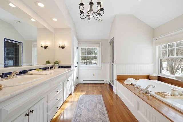 full bathroom with a sink, a wainscoted wall, a wealth of natural light, lofted ceiling, and a baseboard heating unit